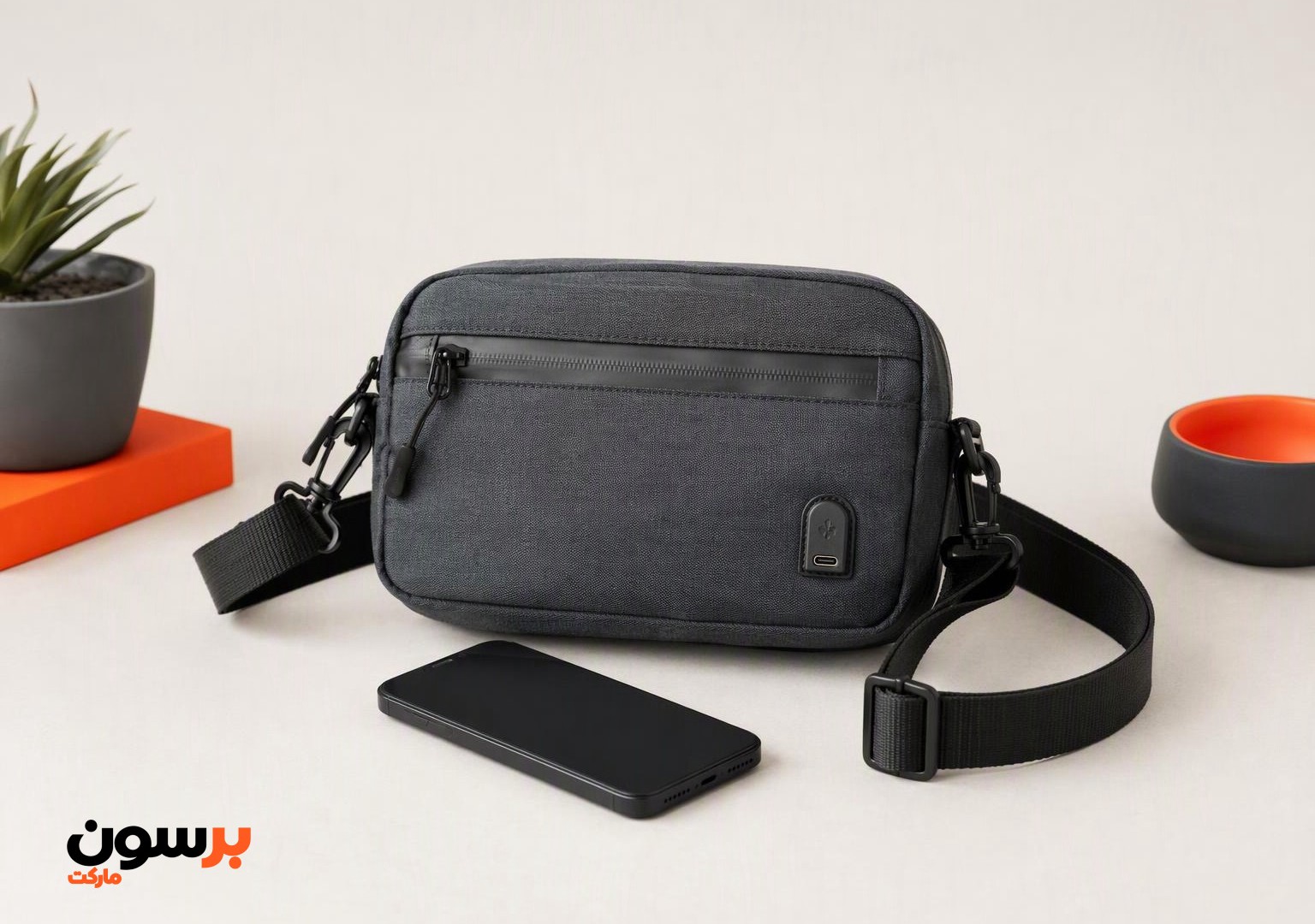 کیف کراس ضد آب USB تیره با گوشی روی میز ساده