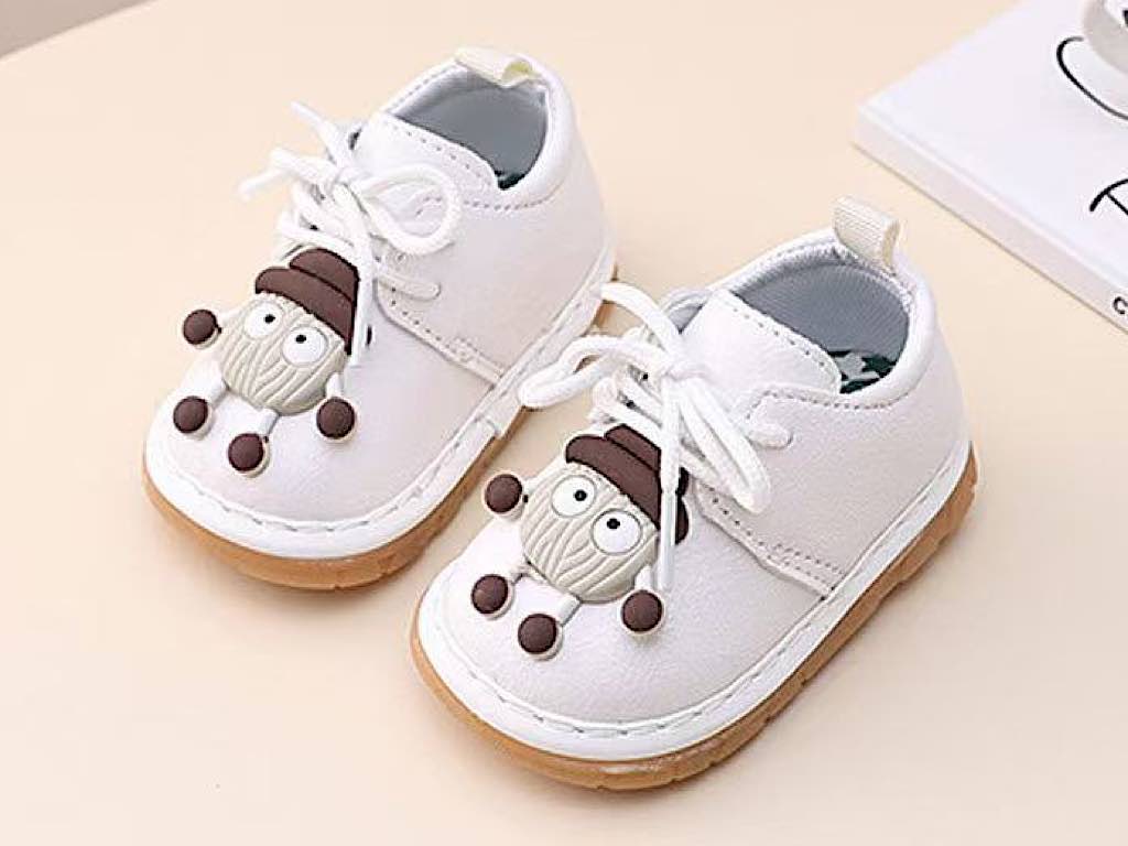 کفش سوتی و جغجغه ای نوزادی شیری رنگ مدل آدمک