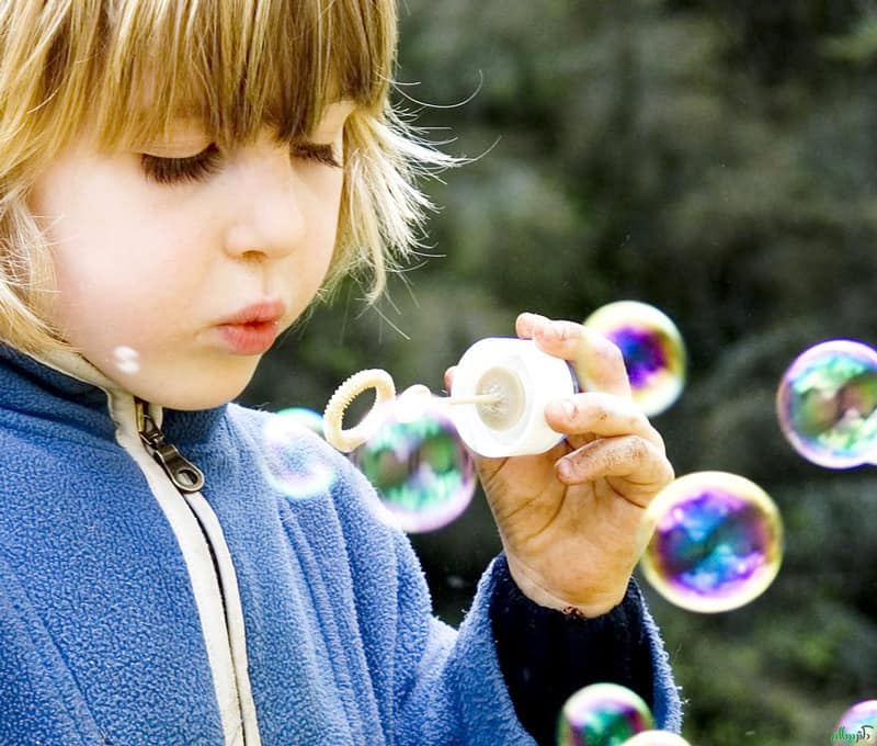 کودکی مشغول بازی با حباب ساز است