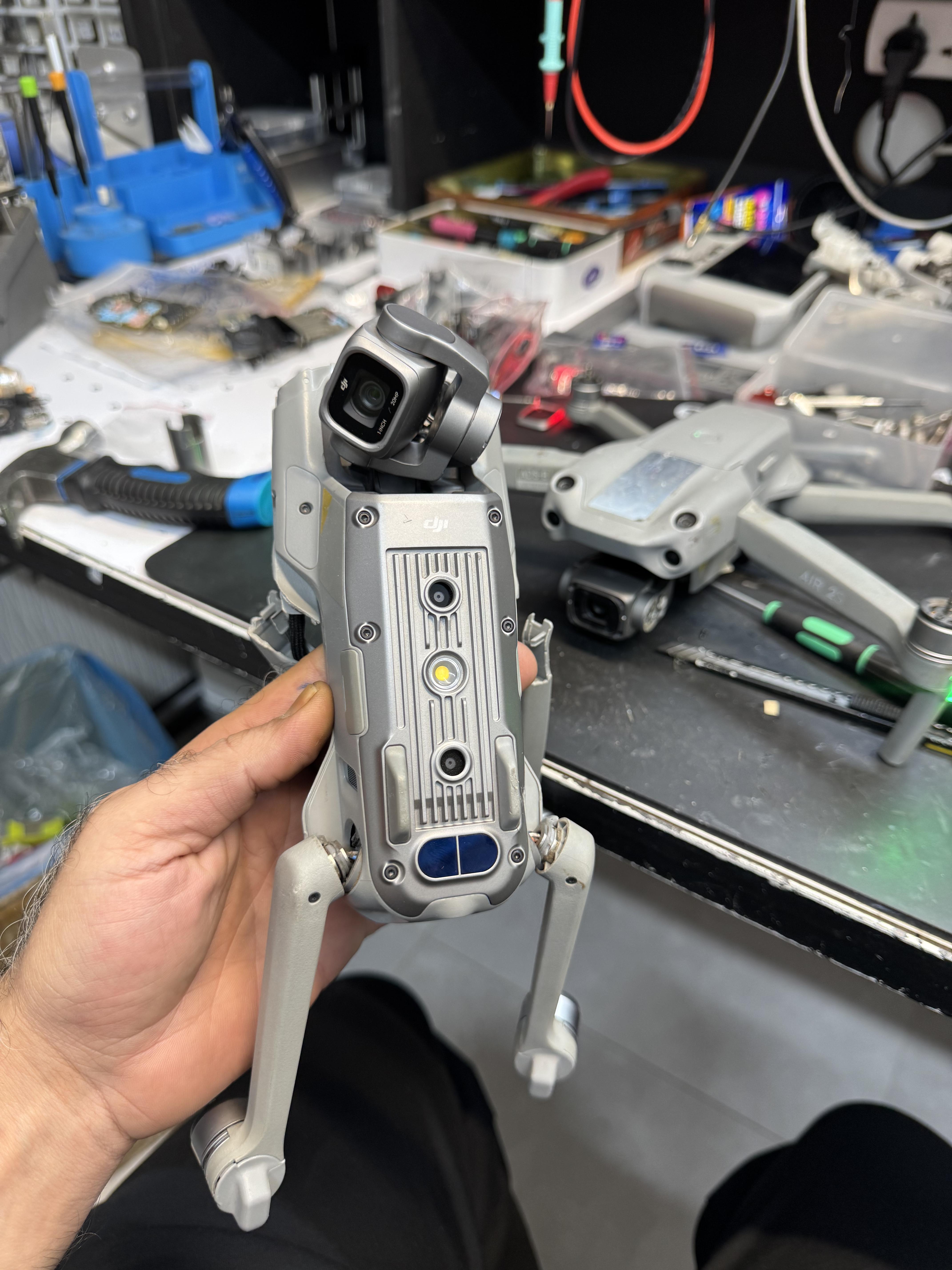 نمای زیرین DJI Air 2S در دست تعمیرکار و محل اتصال بازوها
