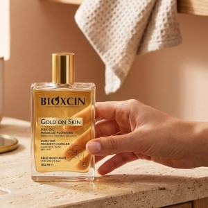بطری روغن خشک درخشان کننده بیوکسین GOLD ON SKIN با رایحه گلی و بافت سبک جذب سریع حجم ۱۰۰ میل